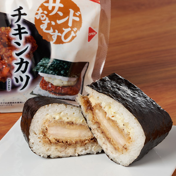サンドおむすび　チキンカツ ファミリーマート ジューシーで柔らかいチキンカツを、野菜・果実の旨みがきいた濃厚ソースとブラックペッパー入りのマヨソースで挟んだおむすび。