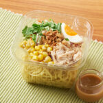 ファミリーマートの【北海道】ラーメンサラダを比較する。税込価格：438円。北海道で支持されている中太ちぢれ麺を使ったラーメンサラダです。5種類の野菜と蒸し鶏、ゆでたまご、コーンをトッピングしています。ごま風味と程よい酸味のごまダレが特徴です。