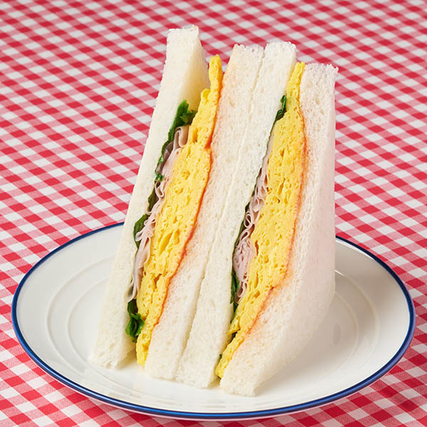 ファミリーマートの【関西】玉子焼&ハムサンドを比較する。税込価格：348円。バターソースが香るふんわり食感の玉子焼とハムを組み合わせたサンドイッチです。