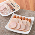 ファミリーマートのソーセージ・チキンハム・スモークチキン燻製3種を比較する。税込価格：398円。桜チップを使用し、燻製させたソーセージ・チキンハム・スモークチキンを盛り合わせた、おつまみにぴったりな商品です。