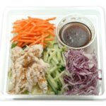 セブンイレブンのシャキシャキ野菜と蒸し鶏のサラダを比較する。税込価格：421円、カロリー：123kcal、1円あたりカロリー：0.29kcal/円、たんぱく質：12g、1円あたりたんぱく質：0.03g/円、脂質：2g、炭水化物：15.8g、糖質：12.5g、食物繊維：3.3g、食塩相当量：2.7g。蒸し鶏と野菜をピリッとした辛みと香りのある柚子胡椒ドレッシングで食べるサラダです。アレルギー：卵、小麦。