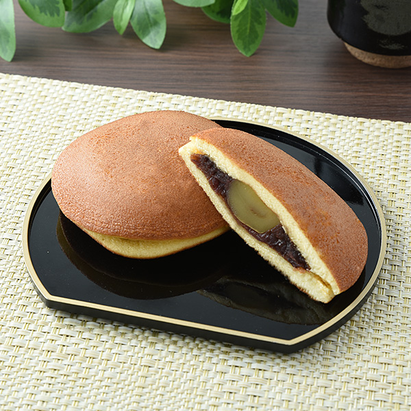 ファミリーマートのまるっと一粒栗どら焼き。税込価格：218円。北海道産小豆を使用したつぶあんに一粒栗をまるっとのせ、国産小麦を自社でブレンドしたしっとりくちどけの良い生地ではさんだどら焼きです。