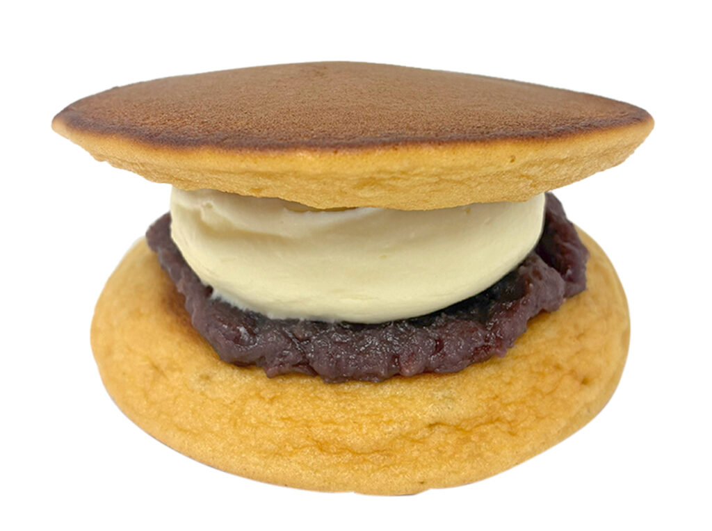 セブンイレブンの粒あん＆バタークリームどらを比較する。税込価格：238円、カロリー：321kcal、1円あたりカロリー：1.35kcal/円、たんぱく質：5.8g、1円あたりたんぱく質：0.02g/円、脂質：15.2g、炭水化物：41.2g、糖質：39.5g、食物繊維：1.7g、食塩相当量：0.6g。ふんわりしっとりした食感を感じられるどら焼き生地に、十勝産小豆の粒あんと相性の良いバタークリームをトッピングしたどら焼き。アレルギー：卵、乳、小麦。