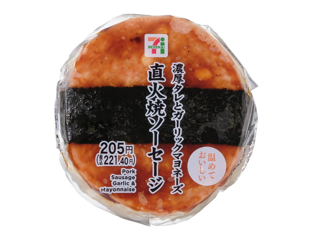 セブンイレブンの直火焼ソーセージおむすびを比較する。税込価格：221円、カロリー：307kcal、1円あたりカロリー：1.39kcal/円、たんぱく質：6.6g、1円あたりたんぱく質：0.03g/円、脂質：15.4g、炭水化物：36.3g、糖質：34.7g、食物繊維：1.6g、食塩相当量：2.2g。厚みのあるソーセージに、照り焼きタレとガーリックマヨネーズを合わせたおむすびです。アレルギー：卵、乳、小麦。