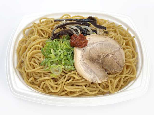 セブンイレブンの豚骨焼ラーメン 辛みそ添えを比較する。税込価格：464円、カロリー：614kcal、1円あたりカロリー：1.32kcal/円、たんぱく質：22.4g、1円あたりたんぱく質：0.05g/円、脂質：20.8g、炭水化物：87.1g、糖質：81.6g、食物繊維：5.5g、食塩相当量：5.7g。辛みそが味のアクセントになる、マー油とネギ油香る豚骨ベースの焼ラーメンです。アレルギー：卵、乳、小麦。