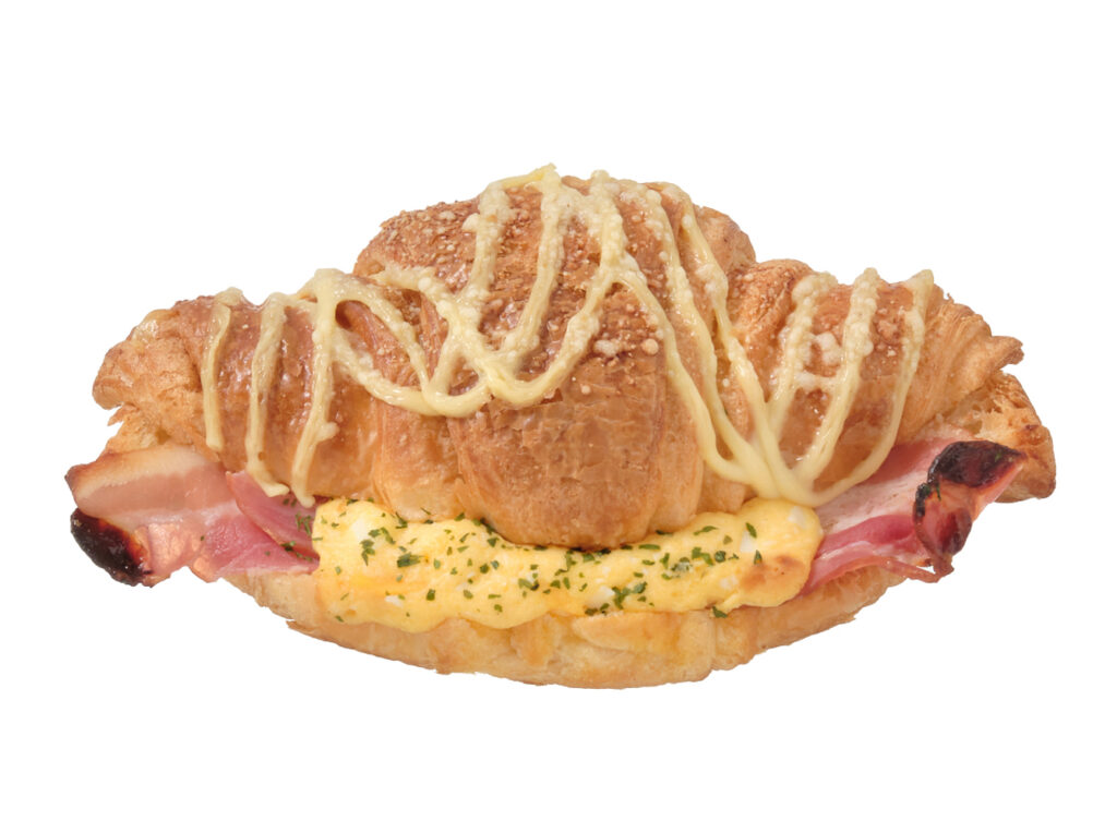 セブンイレブンのクロワッサン ベーコンエッグを比較する。税込価格：246円、カロリー：406kcal、1円あたりカロリー：1.65kcal/円、たんぱく質：8.8g、1円あたりたんぱく質：0.04g/円、脂質：26.1g、炭水化物：34.6g、糖質：33.5g、食物繊維：1.1g、食塩相当量：2g。香ばしく焼き上げたクロワッサンにベーコン，たまごフィリングを挟み、マヨネーズソース，チーズをトッピングして焼き上げた食事として楽しめる惣菜系のクロワッサンです。アレルギー：卵、乳、小麦。