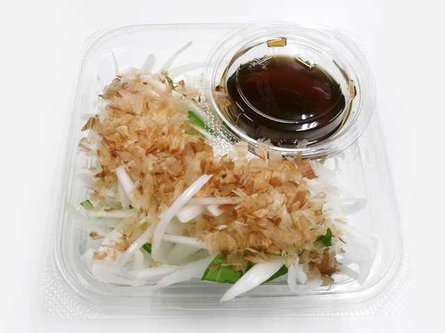 セブンイレブンの新玉ねぎサラダを比較する。税込価格：246円、カロリー：51kcal、1円あたりカロリー：0.21kcal/円、たんぱく質：2.4g、1円あたりたんぱく質：0.01g/円、脂質：0.4g、炭水化物：10.3g、糖質：8.5g、食物繊維：1.8g、食塩相当量：1.7g。広島県因島産の新玉ねぎを使用したサラダです。和風だしの効いたポン酢と鰹節で旨味のある味わいです。アレルギー：小麦。