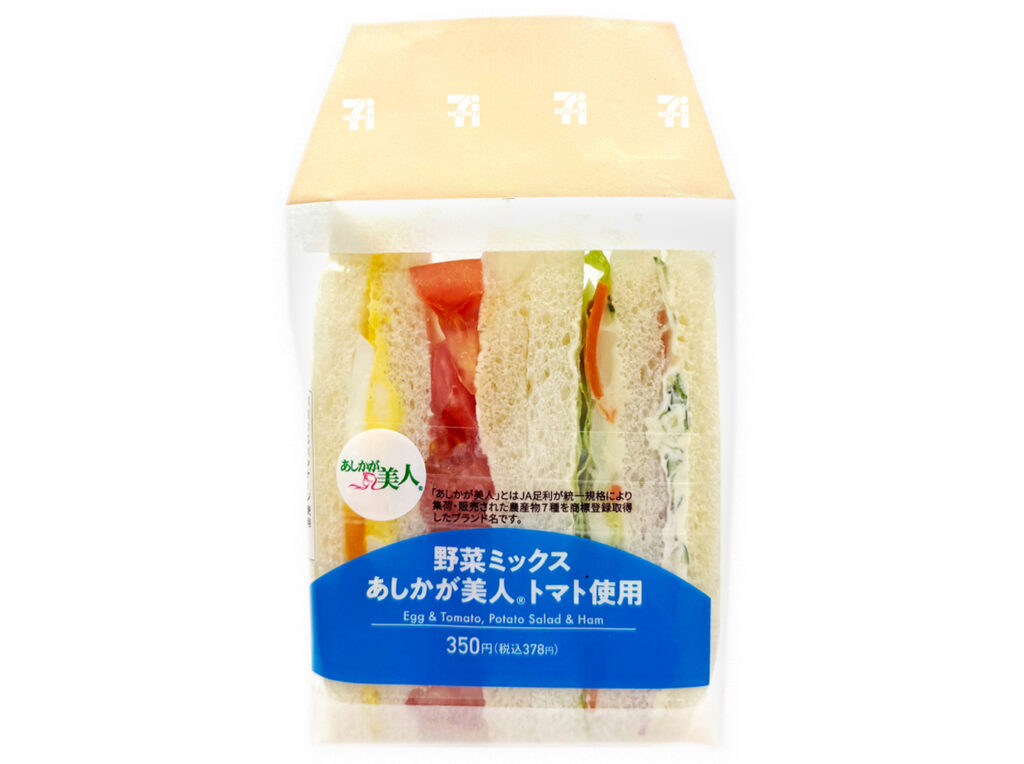 セブンイレブンの野菜ミックスサンド あしかが美人トマト使用を比較する。税込価格：378円、カロリー：314kcal、1円あたりカロリー：0.83kcal/円、たんぱく質：8.7g、1円あたりたんぱく質：0.02g/円、脂質：16.4g、炭水化物：34.1g、糖質：31.7g、食物繊維：2.4g、食塩相当量：1.6g。あしかが美人トマト、たまごサラダ、ハム、野菜を組み合わせた様々な具材を味わえる野菜のミックスサンドです。アレルギー：卵、乳、小麦。