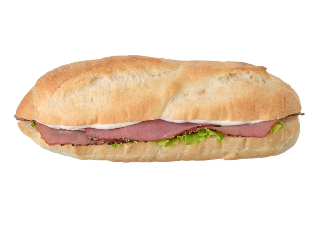 セブンイレブンのバゲットサンド パストラミ＆クリームチーズを比較する。税込価格：322円、カロリー：296kcal、1円あたりカロリー：0.92kcal/円、たんぱく質：10.3g、1円あたりたんぱく質：0.03g/円、脂質：15.2g、炭水化物：30.2g、糖質：28.8g、食物繊維：1.4g、食塩相当量：1.6g。パストラミビーフとクリームチーズ、ピクルス入りのマヨネーズを組み合わせた食べ進みの良いバゲットサンドです。アレルギー：卵、乳、小麦。