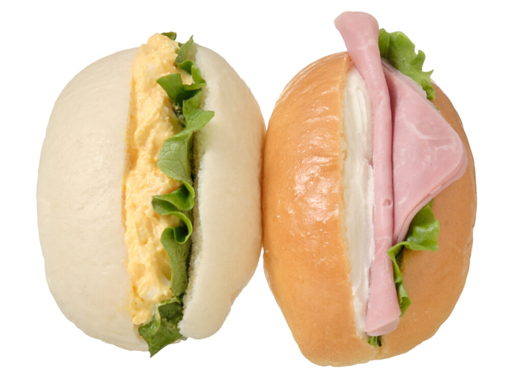 セブンイレブンのミニロールたまごサラダ＆ハムチーズを比較する。税込価格：279円、カロリー：317kcal、1円あたりカロリー：1.14kcal/円、たんぱく質：8.9g、1円あたりたんぱく質：0.03g/円、脂質：18.1g、炭水化物：30.3g、糖質：28.7g、食物繊維：1.6g、食塩相当量：1.3g。生クリーム入りのコッペパンに定番具材のたまごとハム，クリームチーズソースなどを挟み、複数の味わいが楽しめる手軽に持ち運びしやすいボックスタイプのロールパンです。アレルギー：卵、乳、小麦。