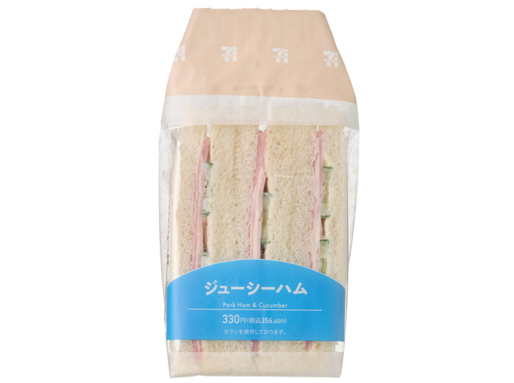 セブンイレブンのジューシーハムサンドを比較する。税込価格：356円、カロリー：355kcal、1円あたりカロリー：1.00kcal/円、たんぱく質：12.2g、1円あたりたんぱく質：0.03g/円、脂質：20.5g、炭水化物：31.2g、糖質：29.6g、食物繊維：1.6g、食塩相当量：1.8g。辛みのあるからしマヨネーズがアクセントのハムと胡瓜サラダを挟みました。アレルギー：卵、乳、小麦。