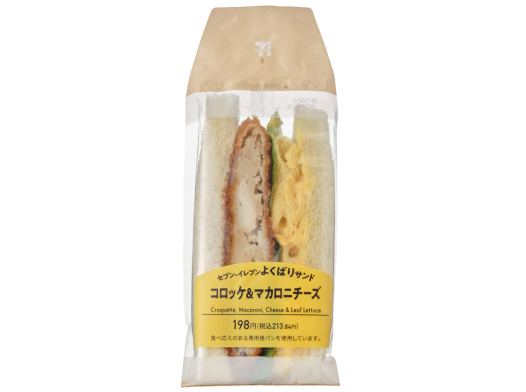 よくばりサンド コロッケ＆マカロニチーズ セブンイレブン 牛肉を使用したコロッケとマカロニチーズを挟んだ重量感のあるサンドイッチ。マカロニチーズのチーズソースにチェダーチーズを使用し、チーズ感の強い味わい。
