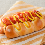 ローソンのあらびきポークフランクロール。税込価格：203円、カロリー：310kcal、たんぱく質：9.3g、脂質：17.9g、炭水化物：28.7g、糖質：27.3g、食物繊維：1.4g、食塩相当量：2g。