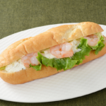 ROLLサンド　海老アボカドソース ローソン ソフトフランスパンにレタス、オニオンマリネ、海老をトッピングし、アボカドとクリームチーズのソースを合わせた商品。具だくさんなカフェ風ロールサンド。
