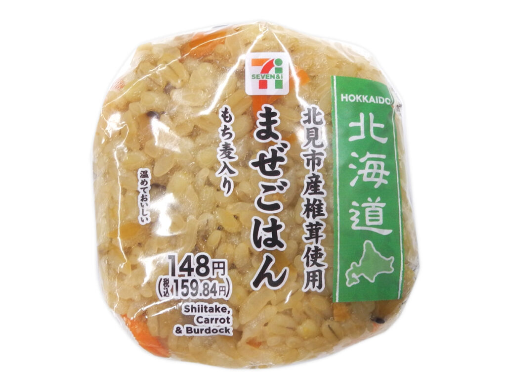 セブンイレブンのもち麦おむすび まぜごはんを比較する。税込価格：160円、カロリー：163kcal、1円あたりカロリー：1.02kcal/円、たんぱく質：3.7g、1円あたりたんぱく質：0.02g/円、脂質：0.8g、炭水化物：36.5g、糖質：34.2g、食物繊維：2.3g、食塩相当量：1.5g。ぷちもち食感が楽しめるもち麦を使用し、椎茸やごぼう、いなり揚げ等の具材を混ぜ込んで甘味と旨味のある味わいに仕上げたまぜごはんのおむすびです。アレルギー：小麦。