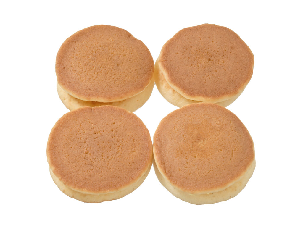 セブンイレブンの７プレミアム パンケーキいちごジャム＆マーガリン ４個入を比較する。税込価格：192円、カロリー：152kcal、1円あたりカロリー：0.79kcal/円、たんぱく質：1.6g、1円あたりたんぱく質：0.01g/円、脂質：6.9g、炭水化物：21g、糖質：20.6g、食物繊維：0.4g、食塩相当量：0.5g。ふんわりもっちりとした生地で、いちごジャムとマーガリンをサンドしたパンケーキ４個入です。アレルギー：卵、乳、小麦。