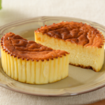 ローソンの盛りすぎ！バスチー −バスク風チーズケーキ−を比較する。税込価格：319円、カロリー：380kcal、たんぱく質：7.4g、脂質：24.4g、炭水化物：32.8g、糖質：32.5g、食物繊維：0.3g、食塩相当量：0.5g。総重量が51％増量！レアでもベイクドでもない、チーズケーキ。アレルギー：卵、乳成分。