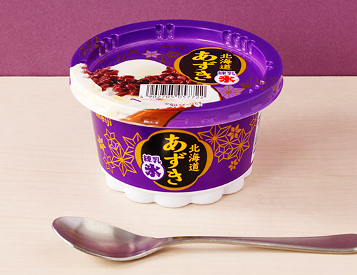 ローソンの明治 北海道あずき 練乳氷を比較する。税込価格：225円、カロリー：207kcal、1円あたりカロリー：0.92kcal/円、たんぱく質：3.6g、1円あたりたんぱく質：0.02g/円、脂質：2g、炭水化物：43.6g、食塩相当量：0.1g。練乳氷とバニラアイスの上に北海道産の粒あずきをたっぷりのせたかき氷アイス。アレルギー：乳成分、大豆。