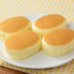 ローソンのチーズ蒸しケーキ 4個入を比較する。税込価格：214円、カロリー：90kcal、1円あたりカロリー：0.42kcal/円、たんぱく質：1.4g、1円あたりたんぱく質：0.01g/円、脂質：3.6g、炭水化物：13.1g、糖質：12.9g、食物繊維：0.2g、食塩相当量：0.1g。ふんわりしっとりとした食感のチーズ蒸しケーキ 4個入。アレルギー：小麦、卵、乳成分、大豆。