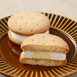 ローソンのしっとりビスケットサンド レアチーズを比較する。税込価格：297円、カロリー：182kcal、1円あたりカロリー：0.61kcal/円、たんぱく質：3g、1円あたりたんぱく質：0.01g/円、脂質：10.6g、炭水化物：18.8g、糖質：18.5g、食物繊維：0.3g、食塩相当量：0.3g。しっとり食感のビスケットと2種のチーズクリームが楽しめるスイーツ。アレルギー：小麦、卵、乳成分、大豆、ゼラチン。