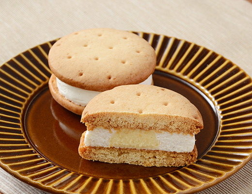 ローソンのしっとりビスケットサンド レアチーズを比較する。税込価格：297円、カロリー：182kcal、1円あたりカロリー：0.61kcal/円、たんぱく質：3g、1円あたりたんぱく質：0.01g/円、脂質：10.6g、炭水化物：18.8g、糖質：18.5g、食物繊維：0.3g、食塩相当量：0.3g。しっとり食感のビスケットと2種のチーズクリームが楽しめるスイーツ。アレルギー：小麦、卵、乳成分、大豆、ゼラチン。