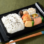 ローソンの和風幕の内弁当を比較する。税込価格：646円、カロリー：496kcal、たんぱく質：17.5g、脂質：12g、炭水化物：81.6g、糖質：77.6g、食物繊維：4g、食塩相当量：1.8g。焼鮭、野菜かき揚げ、シューマイ、玉子焼、小松菜と人参のごま和え、煮物が入ったいろいろなおかずが楽しめる幕の内です。アレルギー：えび、かに、小麦、卵、乳成分、ごま、さけ、大豆、鶏肉、豚肉、ゼラチン。